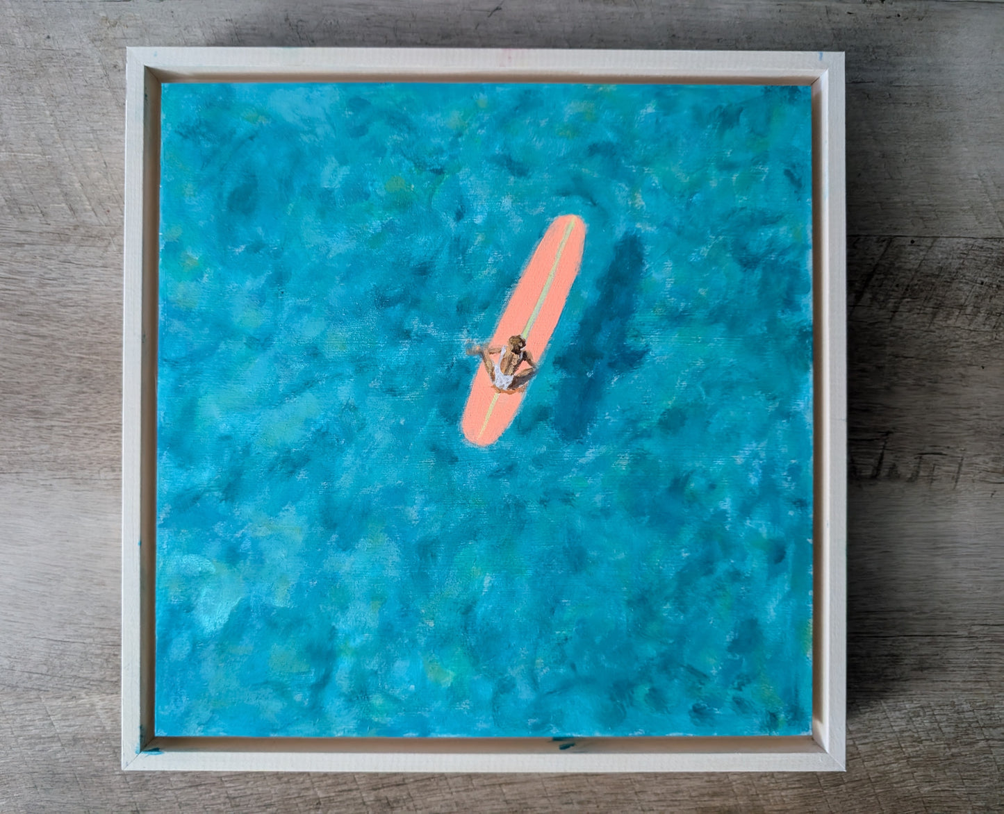 Teal ocean surfer painting on wood panel, aerial view of woman on coral pink surfboard in turquoise water